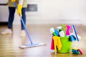 Bucket with cleaning items with modern kitchen and background. Washing brush and spray set with copy space.